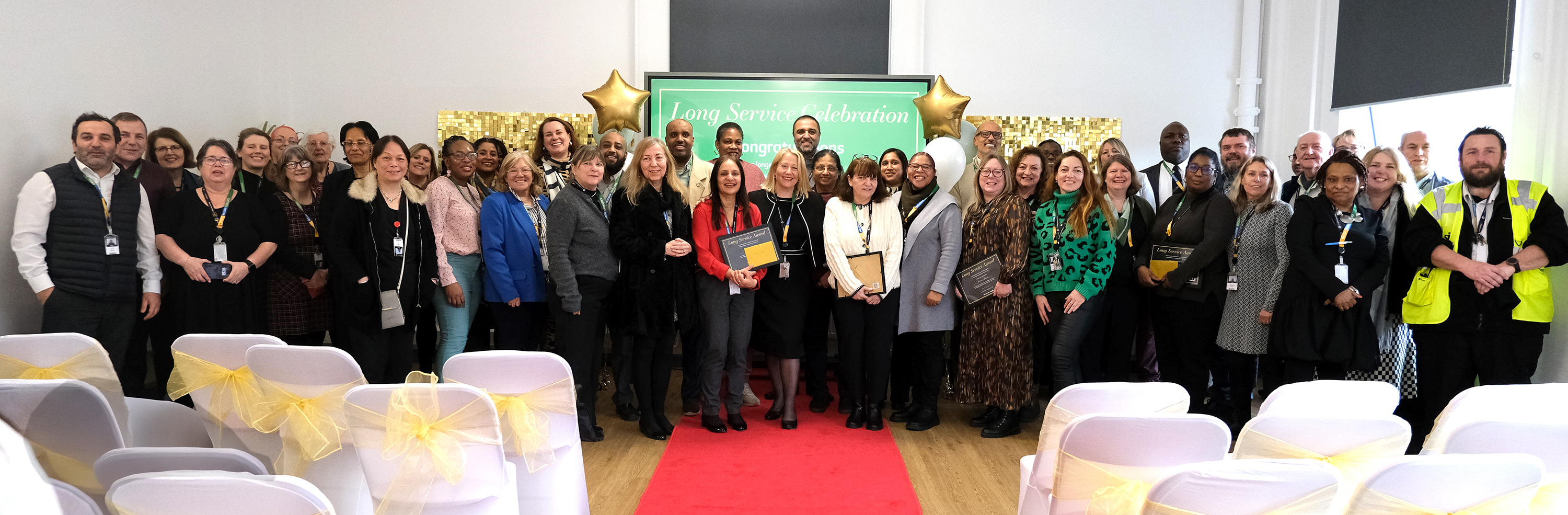 Long Service staff from 10 to 35 years All staff who attended the event stand in a long line in front of red carpet for photograph
